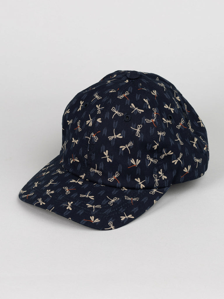 The Japanese Print Cotton Baseball Cap by ID Menswear is crafted from dark blue Japanese cotton featuring white dragonflies, made in Brooklyn and displayed at an angle on a plain white background.